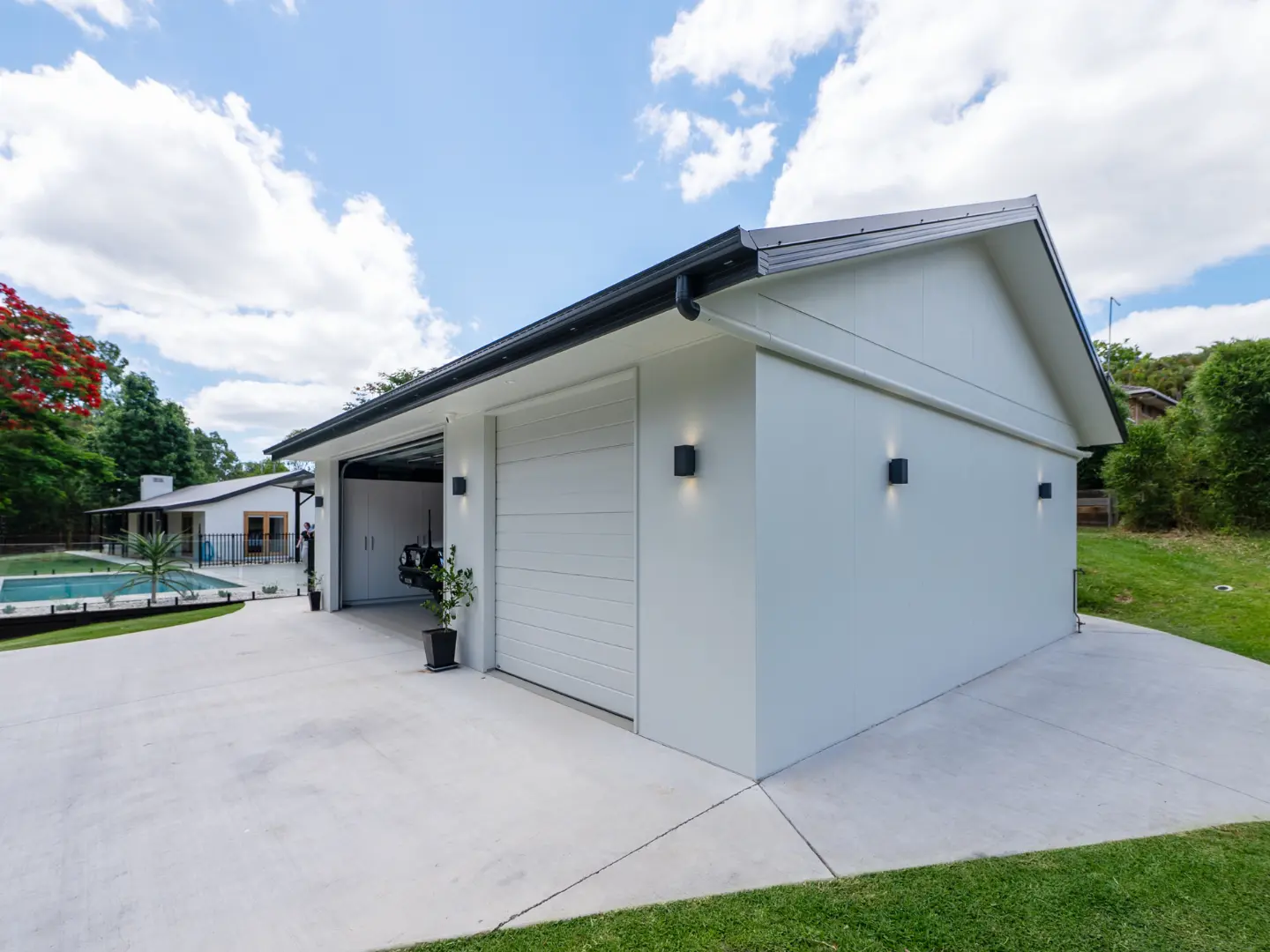 A stylish garage adjacent to a swimming pool in a lush outdoor setting.