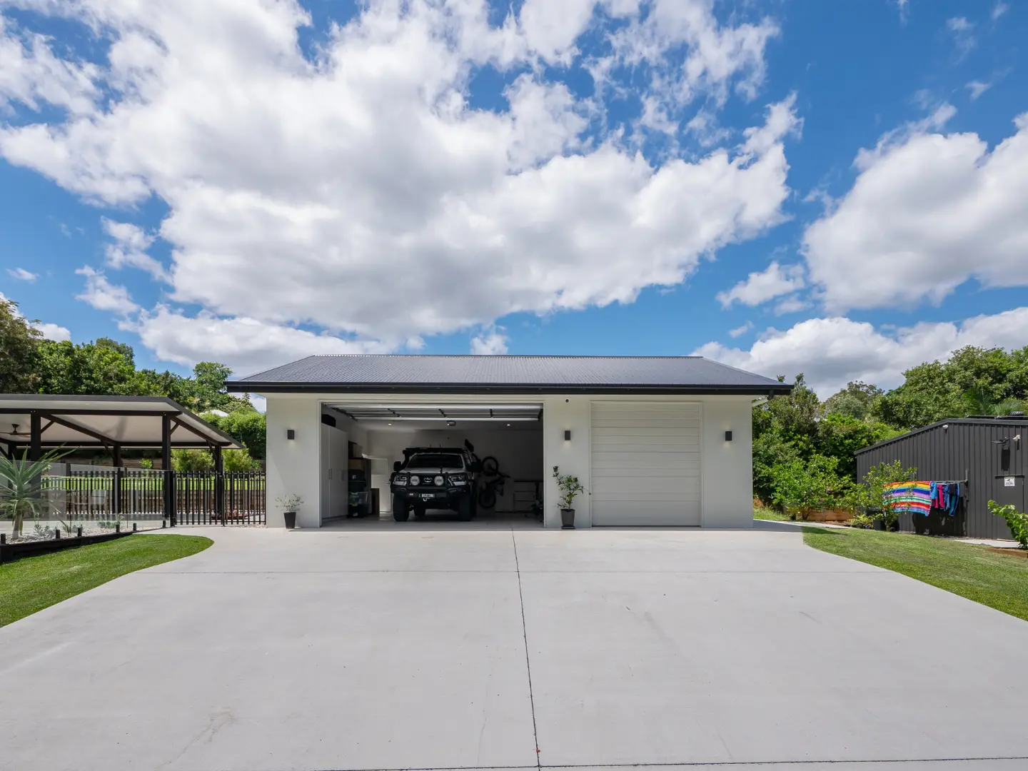 A modern garage with a sleek design and a vehicle parked inside under a blue sky.