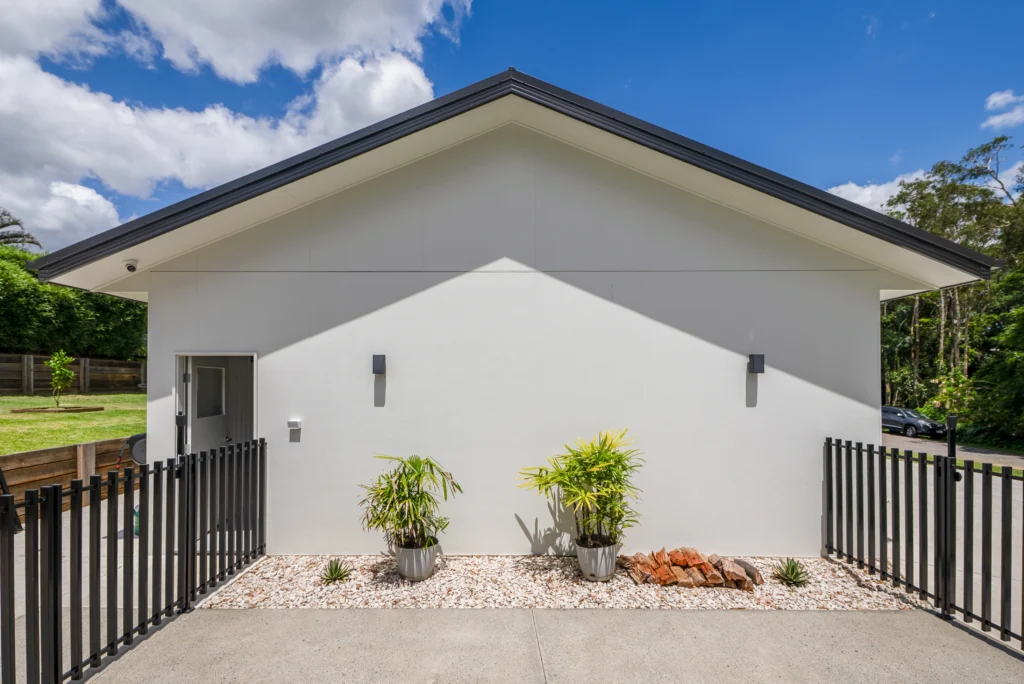 Custom rendered garage exterior with Colorbond roof, black steel fencing and low maintenance landscaping, Sunshine Coast by Bozcon Construct