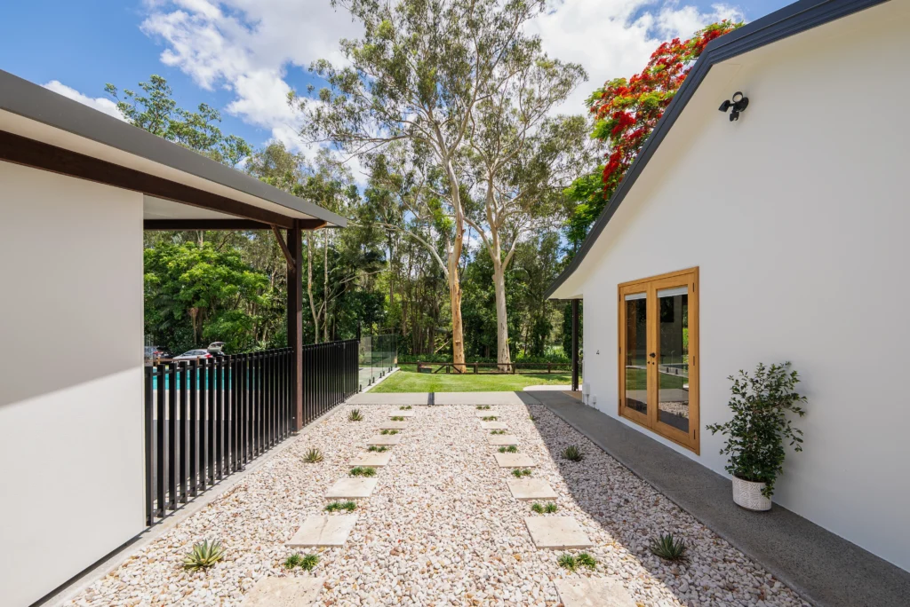 Modern home exterior with rendered walls, timber French doors, gravel garden path and covered alfresco area, Sunshine Coast by Bozcon Construct
